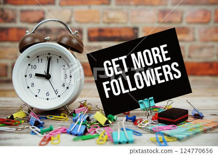 Get More Followers text on paper card with alarm clock and stationary on wooden background Get More Followers text on paper card with alarm clock and stationary on wooden background 124770656