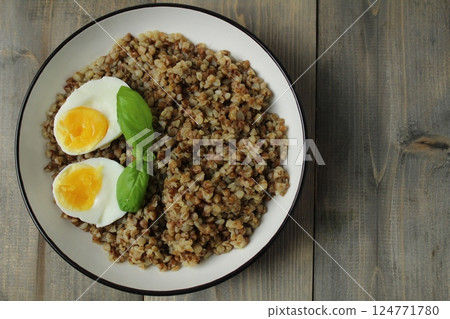 buckwheat porridge egg basil greens in a bowl on a gray fnon with copyspace space for text. Concept of new useful products buckwheat porridge egg basil greens in a bowl on a gray fnon with copyspace space for text. Concept of new useful products 124771780