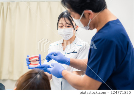 A dentist explaining dental treatment using a tooth model 124771830