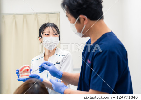 A dentist explaining dental treatment using a tooth model 124771840