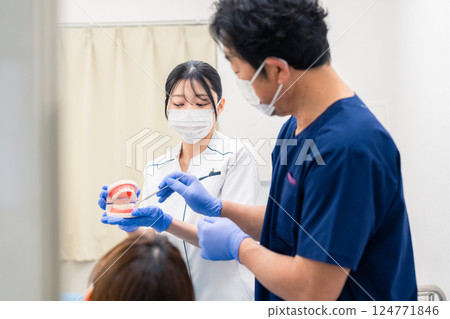 A dentist explaining dental treatment using a tooth model 124771846