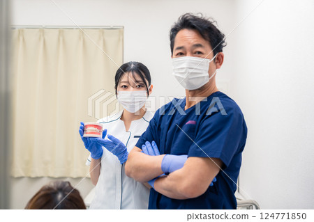 A dentist explaining dental treatment using a tooth model 124771850