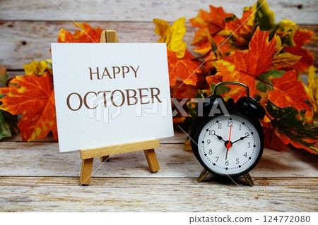 Happy October text with alarm clock and maple leaf decoration on wooden background 124772080