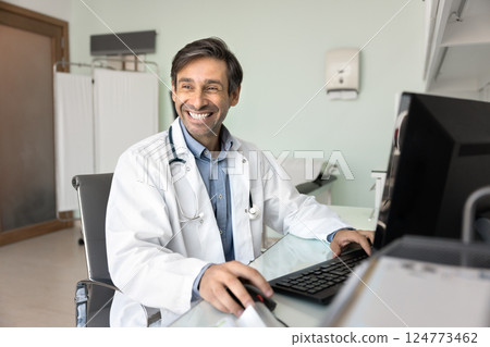 Laughing therapist sitting at desk working on computer 124773462