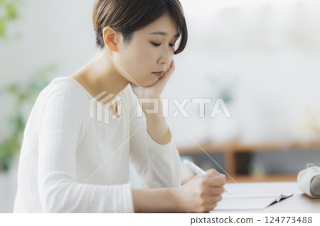 A woman in her 30s studying in the living room A woman in her 30s studying in the living room 124773488
