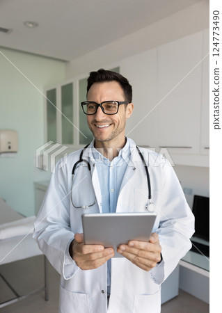 Smiling doctor dressed in white medical coat holding digital tablet Smiling doctor dressed in white medical coat holding digital tablet 124773490