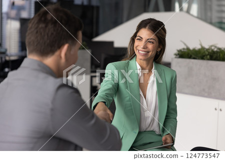 Happy confident Hispanic manager woman shaking hands with male partner Happy confident Hispanic manager woman shaking hands with male partner 124773547