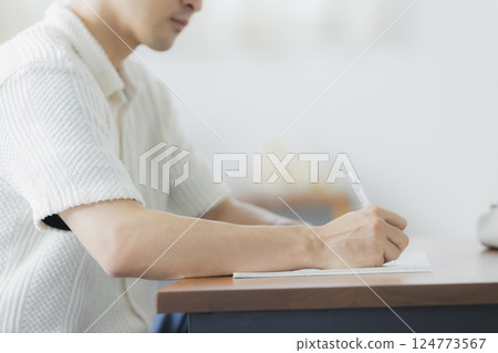 A man in his 30s studying in the living room 124773567