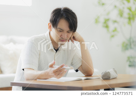 A man in his 30s studying in the living room 124773571