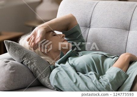 Elderly woman rest with closed eyes hold hand on head 124773593