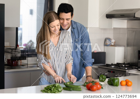 Beautiful couple in love cooking together in kitchen at home Beautiful couple in love cooking together in kitchen at home 124773694