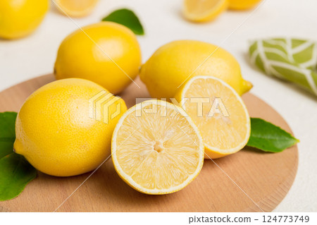 Top view with copy space for fresh and ripe lemons on cutting board. Healthy food background. Elegant background of lemon and lemon slices with squeezer colored background Top view with copy space for fresh and ripe lemons on cutting board. Healthy food background. Elegant background of lemon and lemon slices with squeezer colored background 124773749