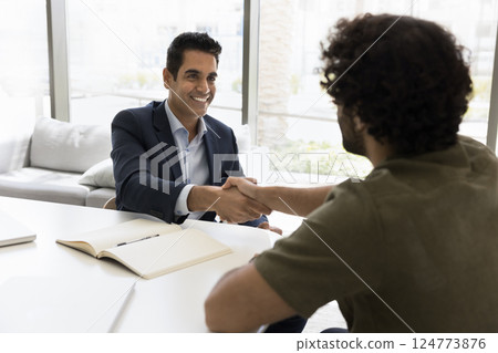 Smiling Indian businessman shaking hands, greeting company client 124773876