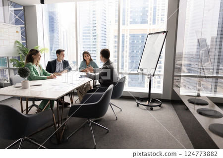 Positive business team sitting at table in office boardroom interior 124773882