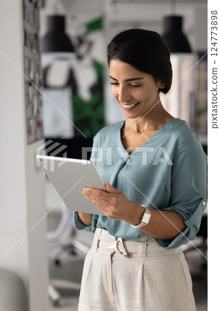 Happy young Hispanic businesswoman working on online project 124773898