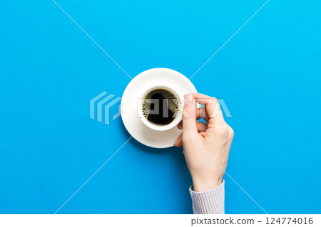 Minimalistic style woman hand holding a cup of coffee on Colored background. Flat lay, top view espresso cup. Empty place for text, copy space. Coffee addiction. Top view, flat lay 124774016