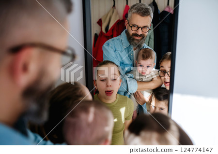 Three sisters, father and newborn brother looking in mirror. 124774147