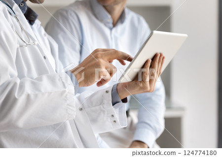 Close up physician holds tablet, demonstrating medical procedures to patient 124774180