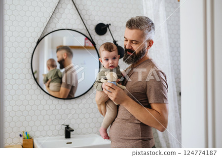 Portrait of father holding baby son in arms. 124774187