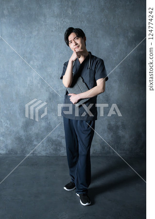 一位穿著手術服的年輕醫師全身抬頭思考 一位穿著手術服的年輕醫師全身抬頭思考 124774242