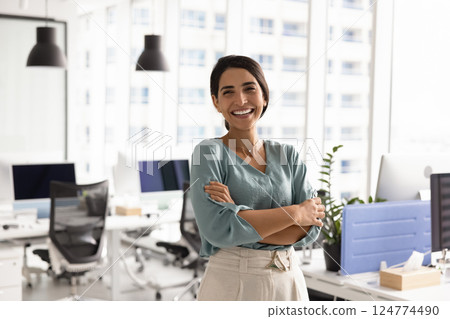 Happy successful female Latin businesswoman posing in office workspace alone Happy successful female Latin businesswoman posing in office workspace alone 124774490