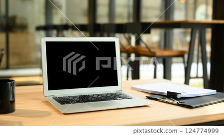 Laptop with empty screen, financial document and coffee cup on wooden desk 124774999