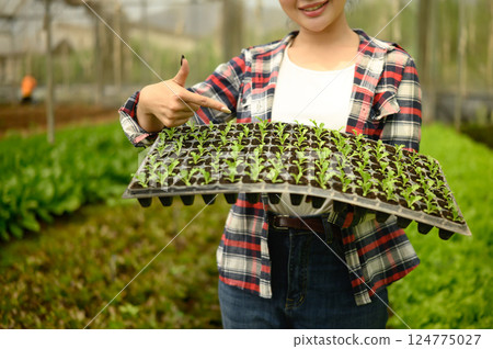 Smiling female farmer showing young plant seedlings. Sustainable agriculture concept Smiling female farmer showing young plant seedlings. Sustainable agriculture concept 124775027