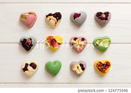 chocolate sweets in the form of a heart with fruits and nuts on a colored background. top view with space for text, holiday concept chocolate sweets in the form of a heart with fruits and nuts on a colored background. top view with space for text, holiday concept 124775046
