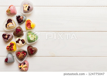 chocolate sweets in the form of a heart with fruits and nuts on a colored background. top view with space for text, holiday concept chocolate sweets in the form of a heart with fruits and nuts on a colored background. top view with space for text, holiday concept 124775047