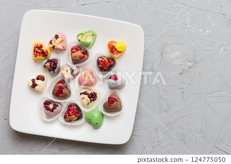 Plate with different chocolate on colored background. Assortment of fine chocolates top view vith copy space Health and obesity concept 124775050