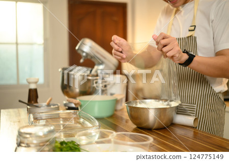 Man covering a mixing bowl of whipped cream with plastic wrap, ready for refrigeration 124775149