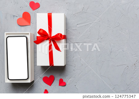Opened gift box with ribbon and phone on color background, top view. Blank open box packaging mockup , Template for your design - branding mockup Opened gift box with ribbon and phone on color background, top view. Blank open box packaging mockup , Template for your design - branding mockup 124775347
