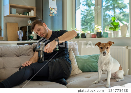 Close-up of man recovery muscle after training, massaging legs with deep tissue massage gun. Sportsman using percussion device for tension and relaxation 124775488