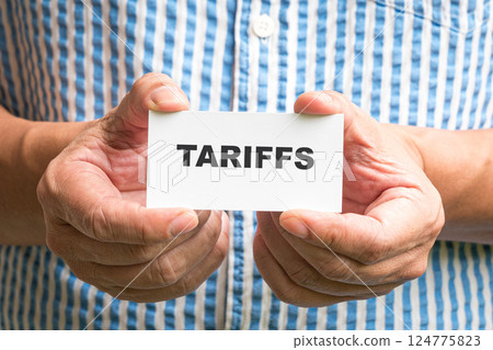 Man holding a white card with Tariffs message. 124775823