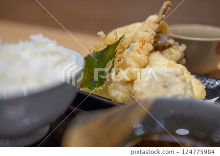 Japanese tempura set featuring crispy shrimp, vegetables, and a deep-fried leaf 124775984