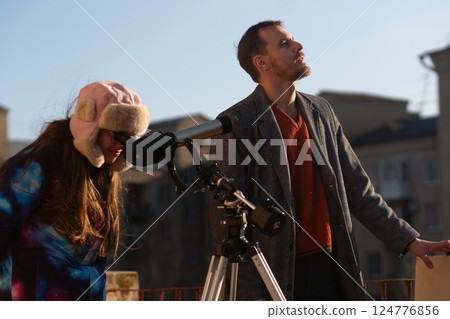 Instructor looks upward while student peers into solar telescope Instructor looks upward while student peers into solar telescope 124776856