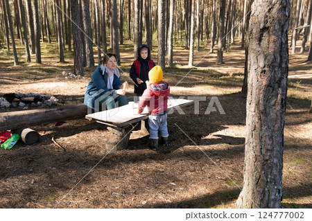 Family enjoying a picnic in a tranquil forest setting during a sunny afternoon 124777002