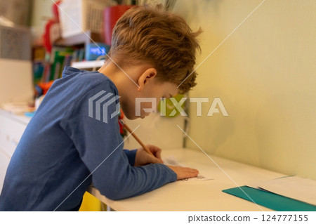 Young boy engaged in creative drawing at home during afternoon hours with focused expression Young boy engaged in creative drawing at home during afternoon hours with focused expression 124777155