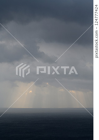 Light shining through the clouds onto the sea Light shining through the clouds onto the sea 124777424