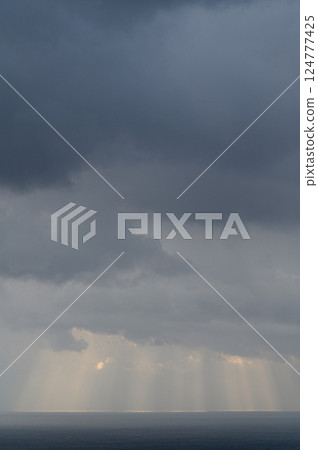 Light shining through the clouds onto the sea Light shining through the clouds onto the sea 124777425