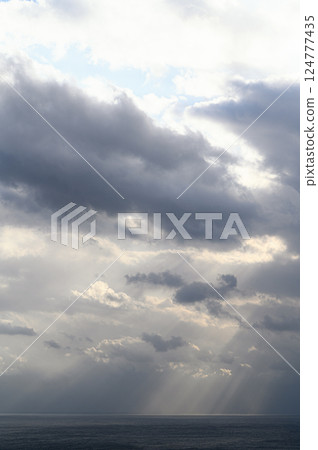 Light shining through the clouds onto the sea Light shining through the clouds onto the sea 124777435