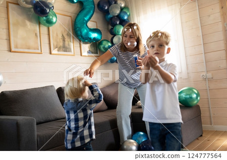 Family celebration with children playing and enjoying bubbles in a cozy living room decorated with 124777564