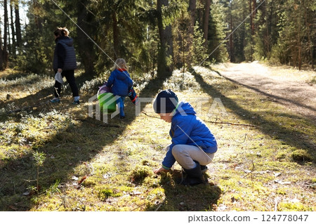 Children exploring a forested area during a sunny day while an adult accompanies them on an outdoor Children exploring a forested area during a sunny day while an adult accompanies them on an outdoor 124778047