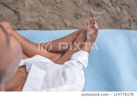 Woman meditating on beach yoga mat, embracing summer mindfulness Woman meditating on beach yoga mat, embracing summer mindfulness 124778176