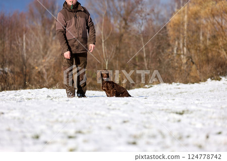 Brown Spaniel running with trainer in snowy winter landscape Brown Spaniel running with trainer in snowy winter landscape 124778742
