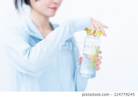 Young woman hydrating during training, no face 124779245