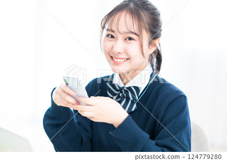 一名高中女生手持智慧型手機微笑 一名高中女生手持智慧型手機微笑 124779280
