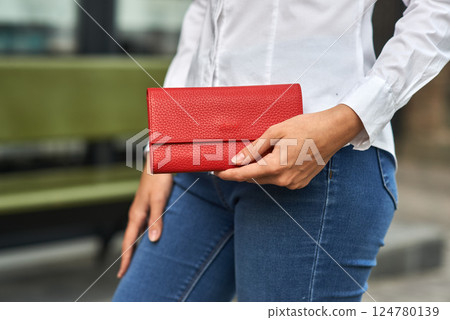 Elegant woman holding fashionable red purse, showcasing style, fashion accessories, street background concept Elegant woman holding fashionable red purse, showcasing style, fashion accessories, street background concept 124780139