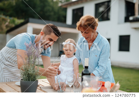 Three generations of family preparing food for a spring weekend barbecue. 124780775
