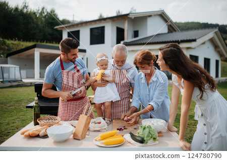 Three generations of family preparing food for a spring weekend barbecue. 124780790